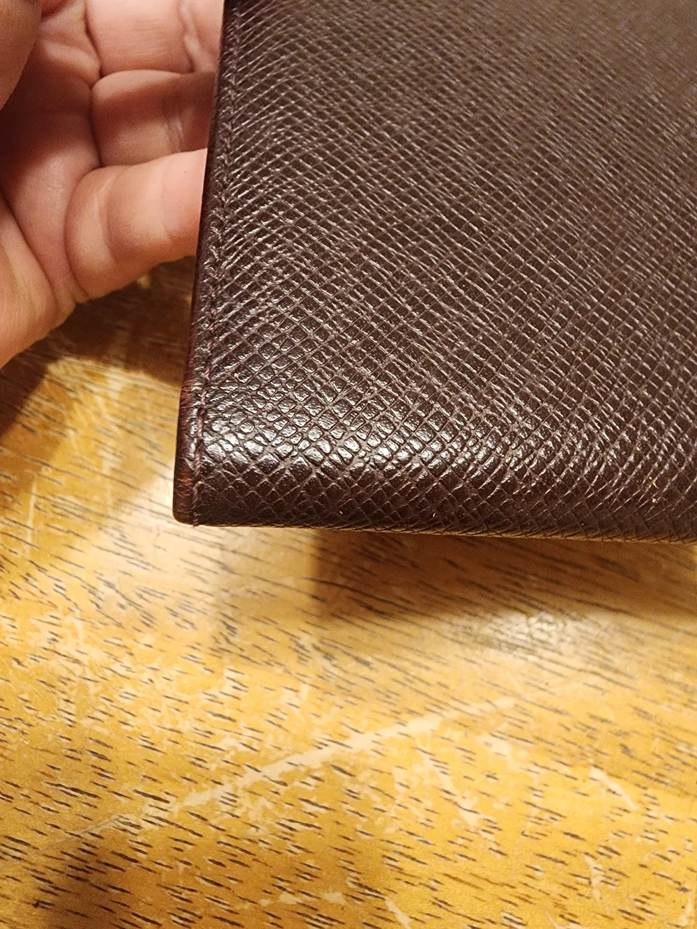 burgandy Louis Vuitton Taiga leather bifold wallet featuring a debossed LV